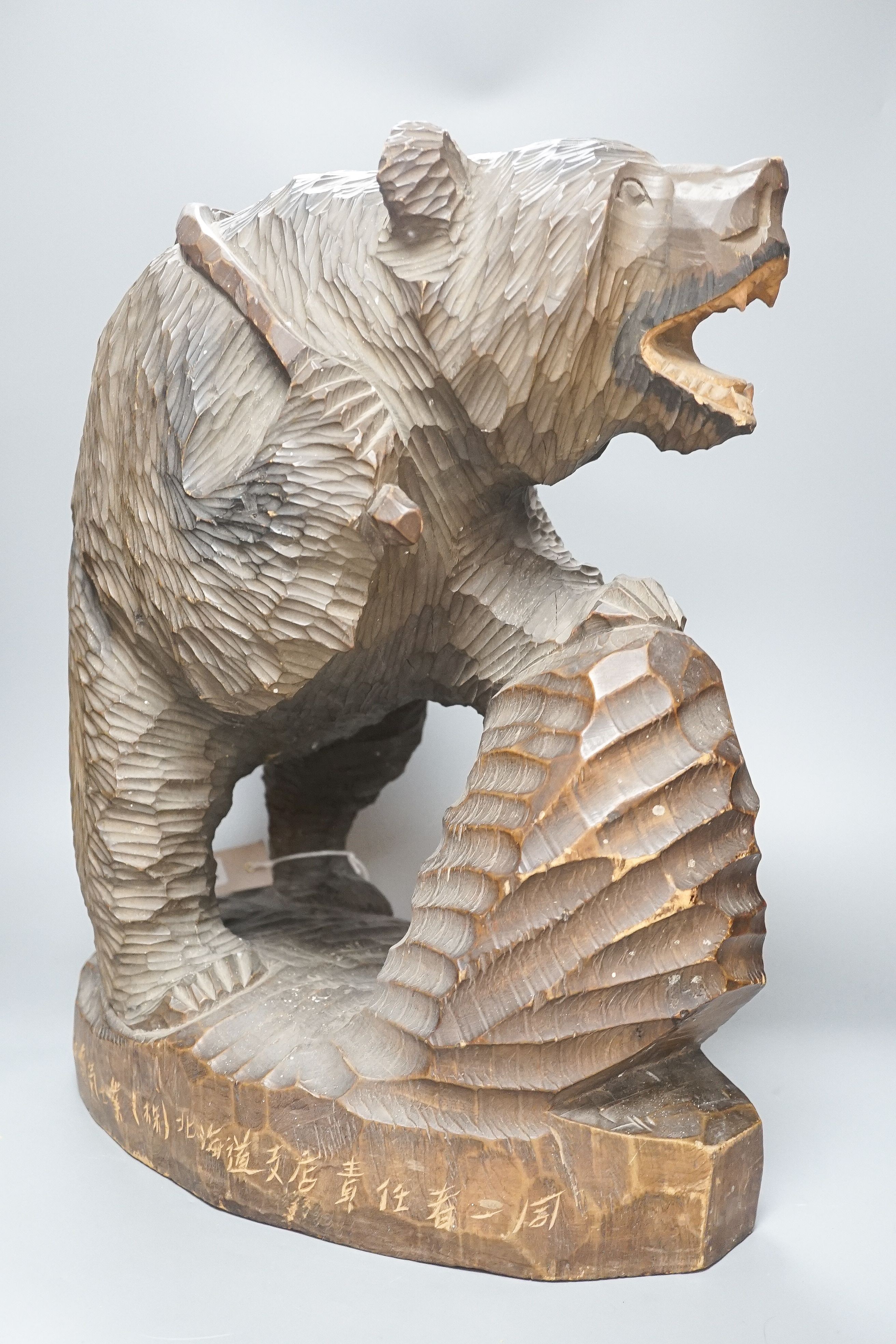 A large Japanese carved wooden bear holding a fish, inscribed 47cm